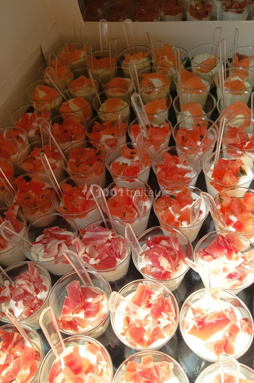 Verrines variées contenant du jambon, du saumon et des morceaux de melon, présentées sur un plateau.