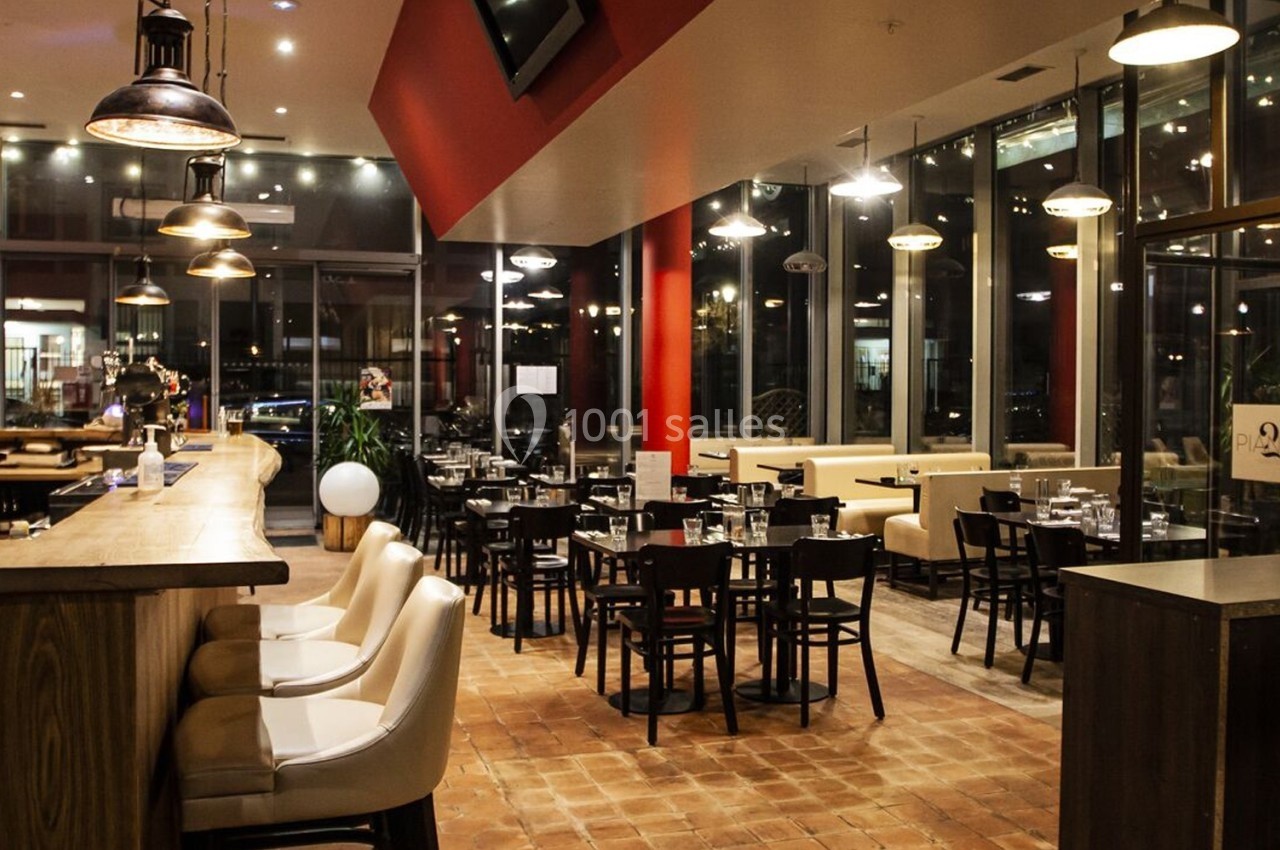 Salle de restaurant moderne avec bar en bois, tables dressées et éclairage chaleureux.