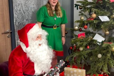 Une femme surveille deux jeunes enfants jouant avec des jouets dans un bac à sable en plein air.
