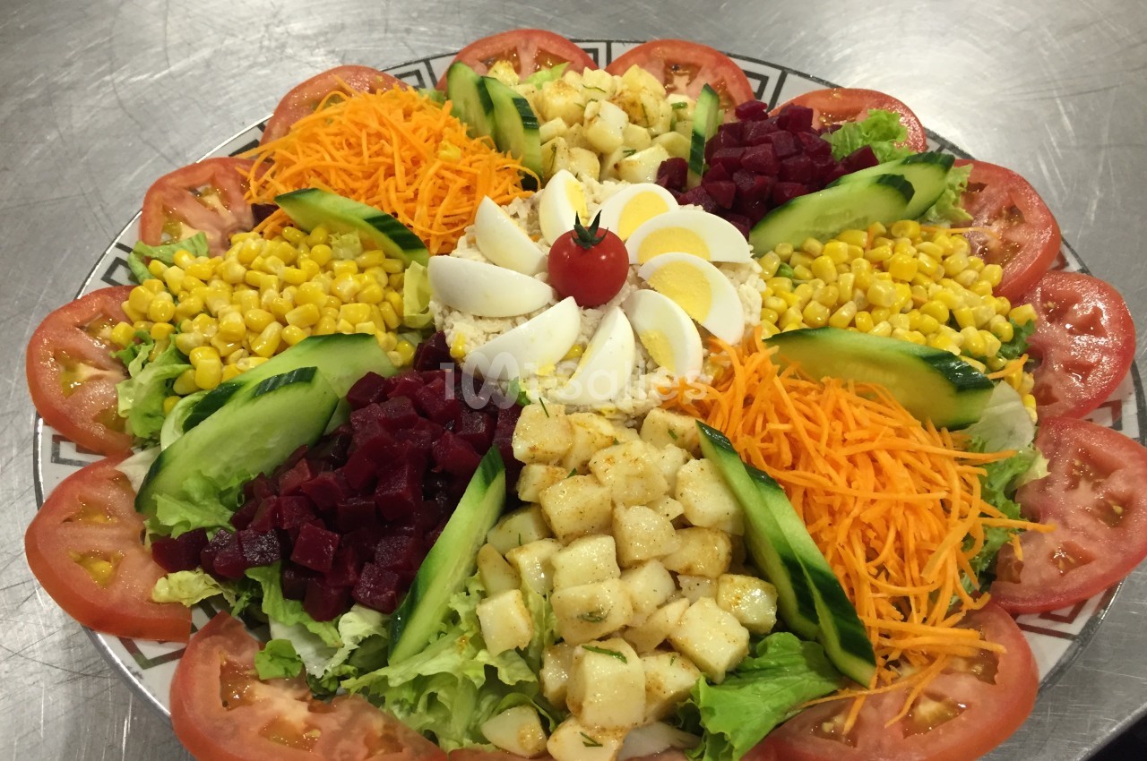 Assiette composée de légumes variés, œufs durs et tomate cerise, disposés en cercle sur un lit de salade.