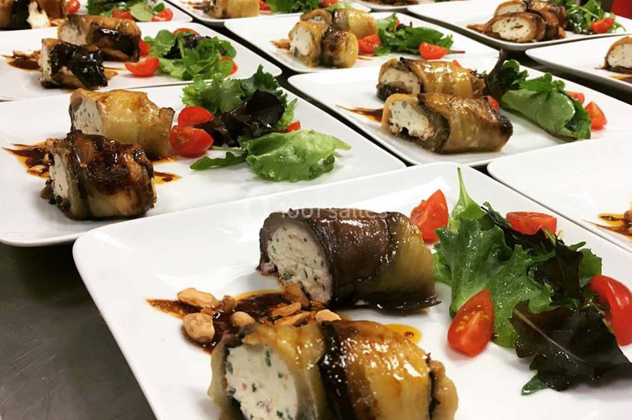 Assiettes dressées avec des roulés d'aubergines farcies, salade verte, tomates cerises et sauce balsamique.