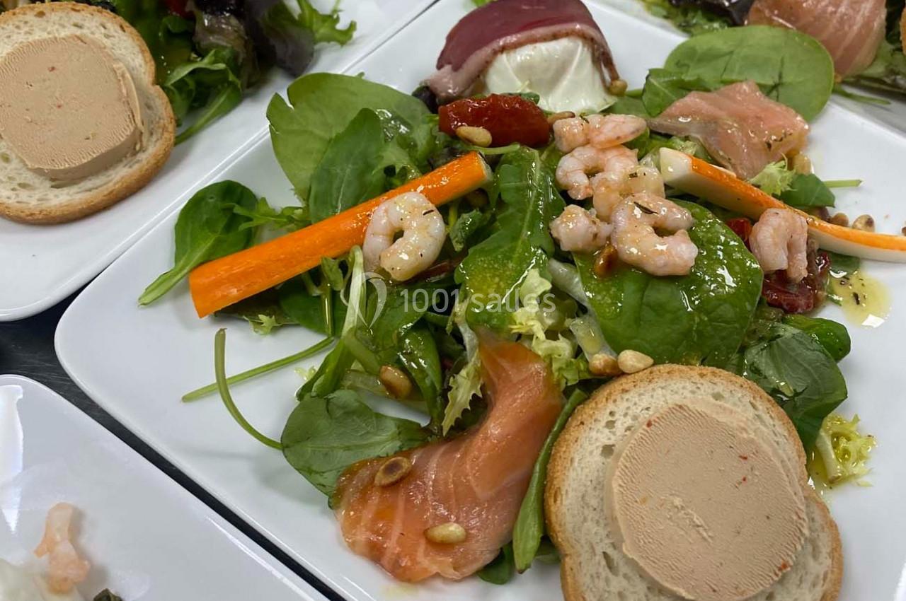 Assiette composée de salade verte, saumon fumé, crevettes, légumes croquants, pain et tranche de foie gras.