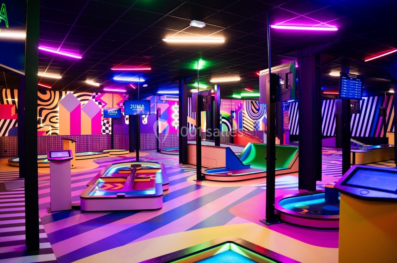 Salle de jeux intérieure colorée avec éclairage néon, pistes interactives et décorations géométriques vibrantes.