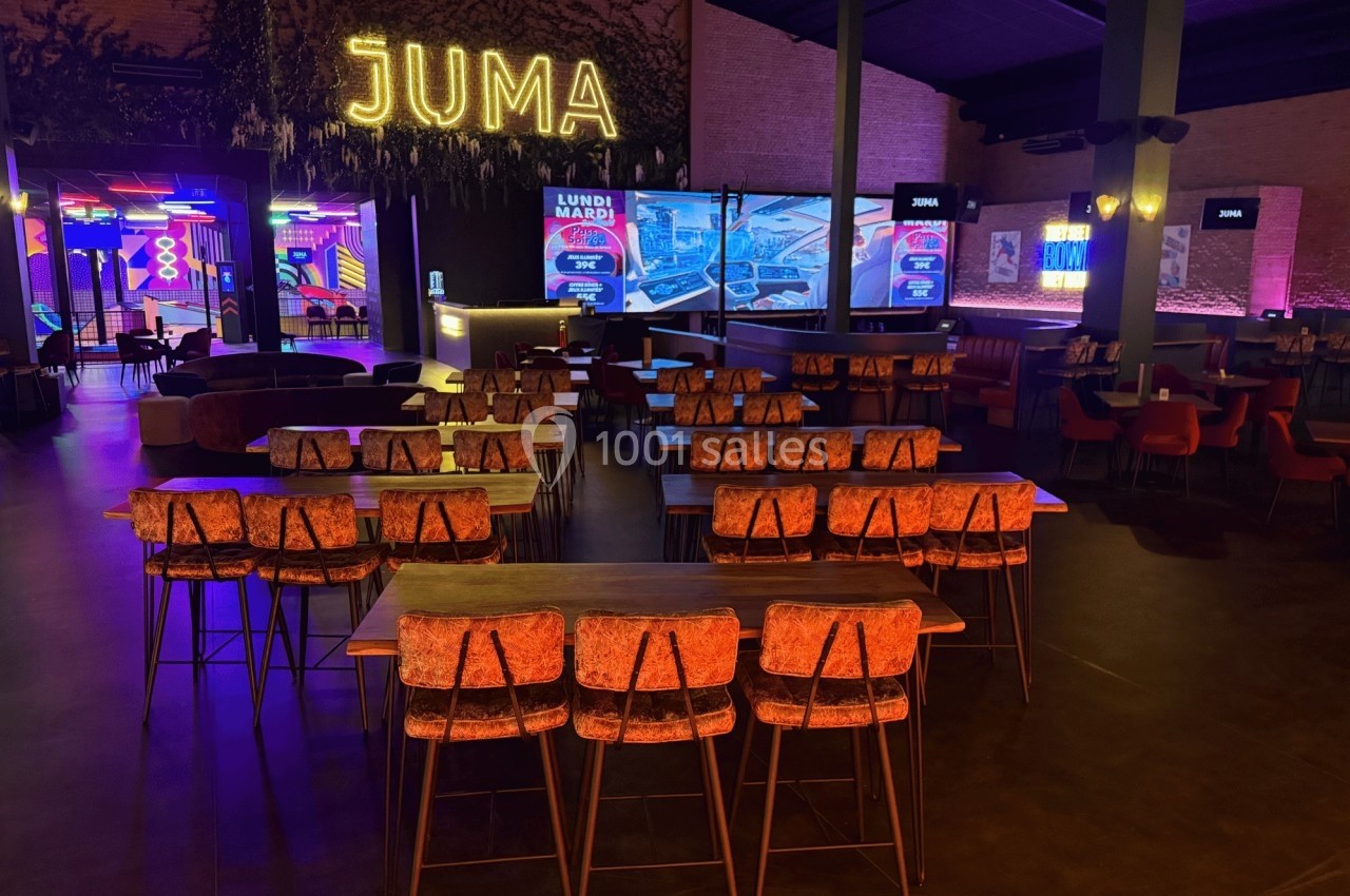 Salle de restaurant avec tables hautes, chaises en bois et éclairage tamisé, décorée de néons colorés.