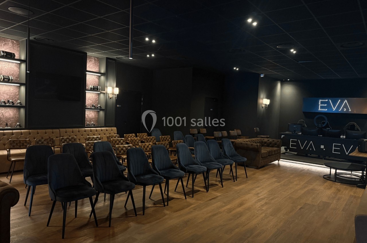 Salle sombre avec rangées de chaises, canapés en cuir, éclairage tamisé et comptoir marqué ’EVA’.