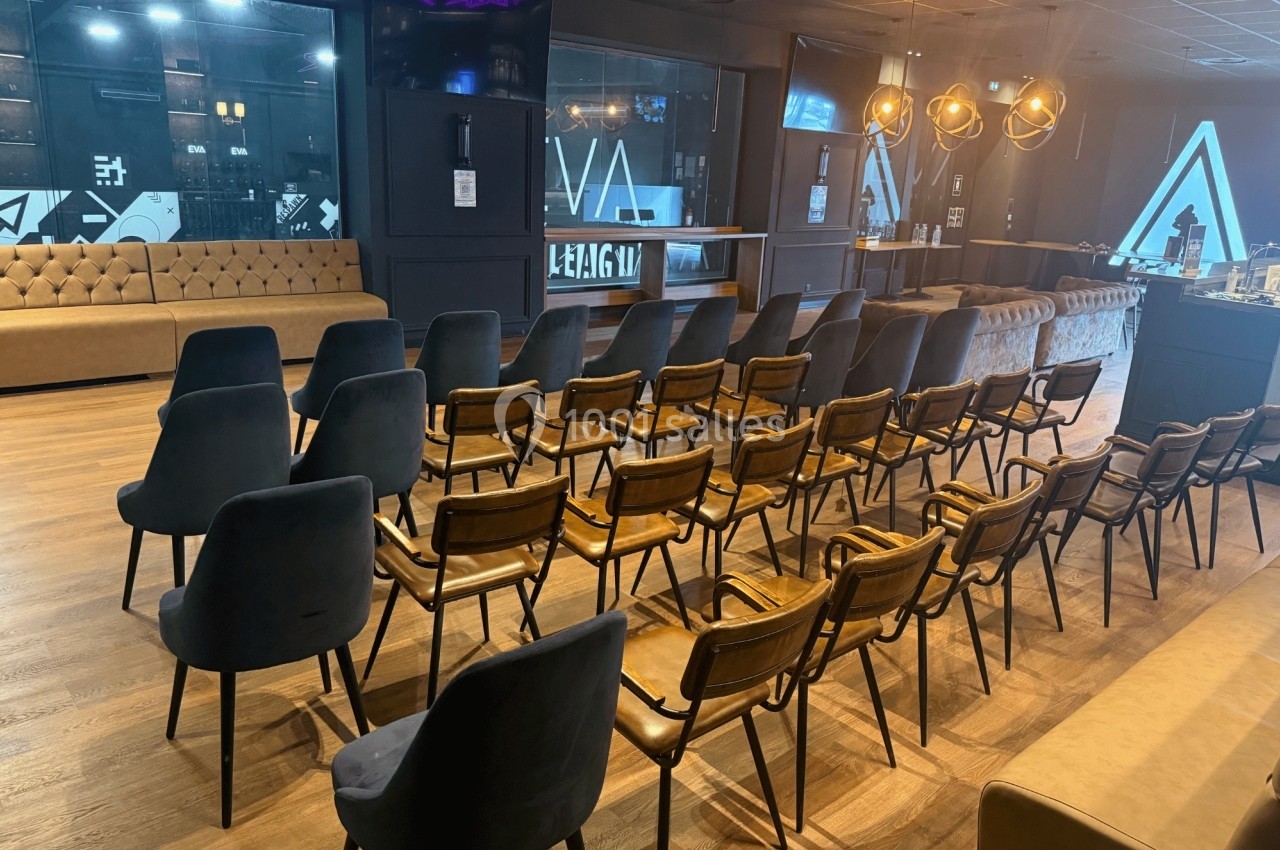 Salle aménagée avec des rangées de chaises en bois et en velours, éclairée par des suspensions modernes.