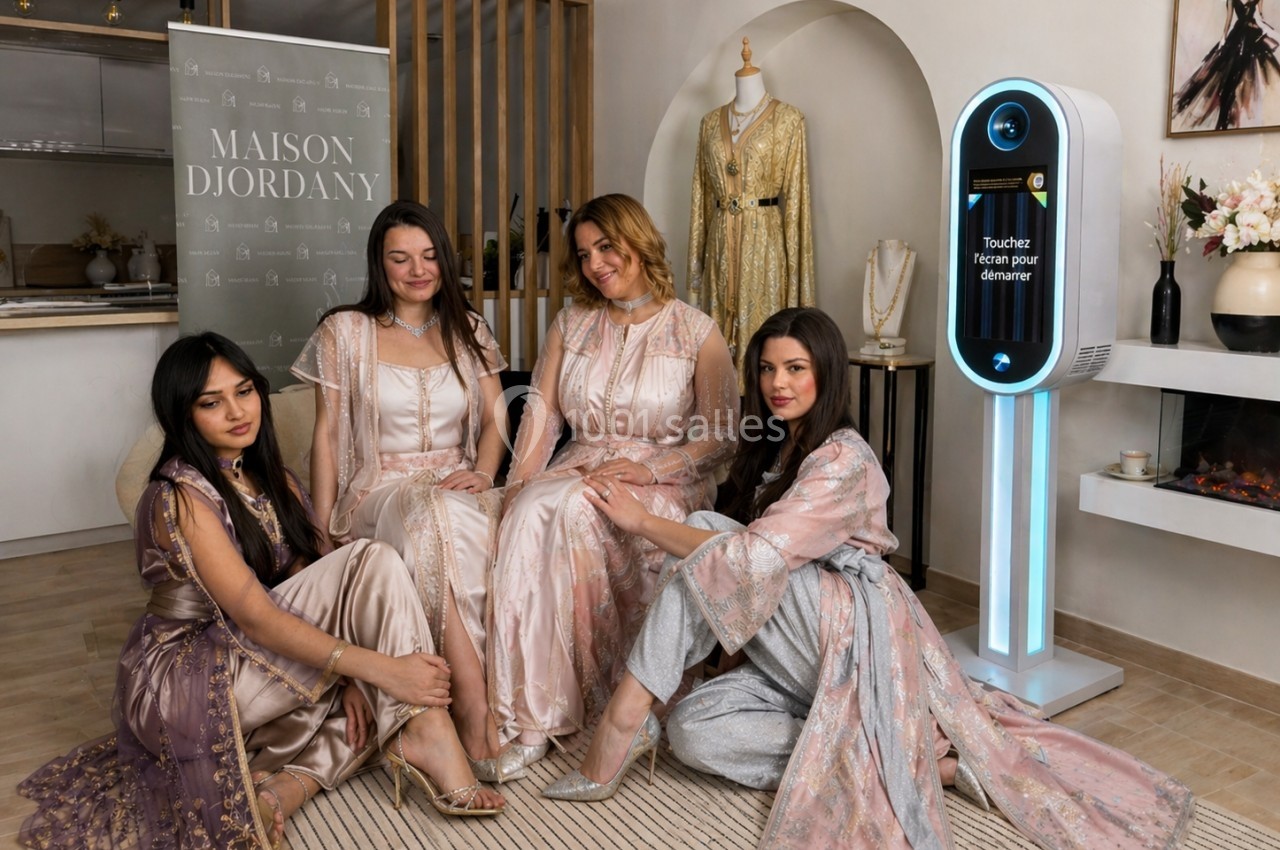 Quatre femmes en robes élégantes posent dans un intérieur raffiné, près d'une borne interactive et d'une bannière.