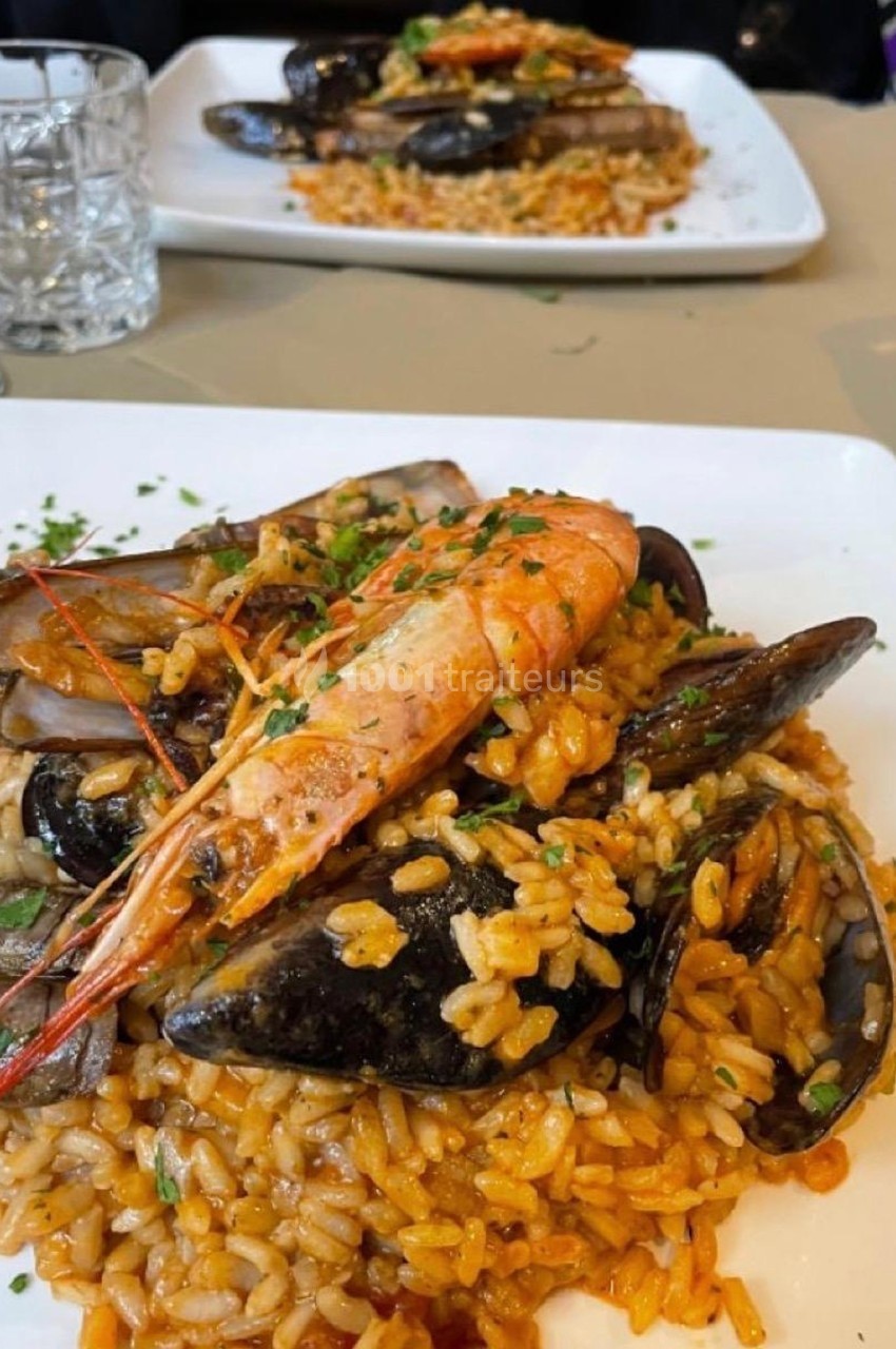 Assiette de riz garnie de fruits de mer variés, dont crevettes, moules et couteaux, servie avec persil frais.