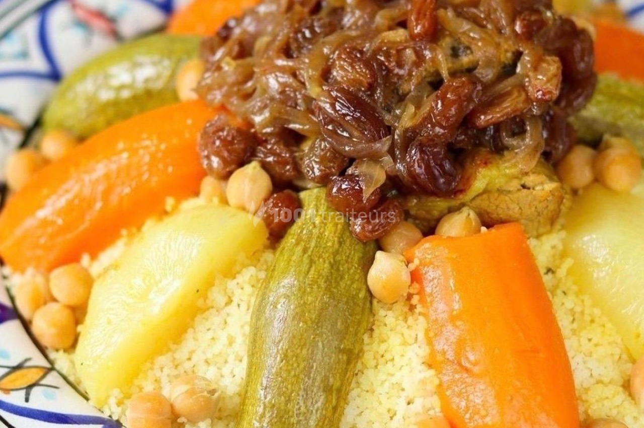 Plat de couscous garni de légumes variés, pois chiches, viande, et oignons caramélisés avec raisins secs.