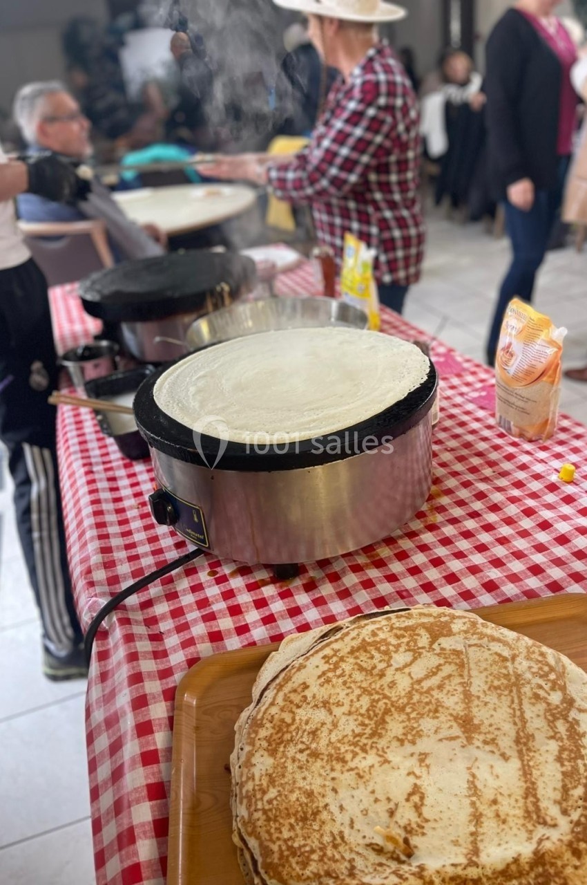 Crêpes en cours de préparation sur des crêpières électriques lors d'un événement convivial en intérieur.