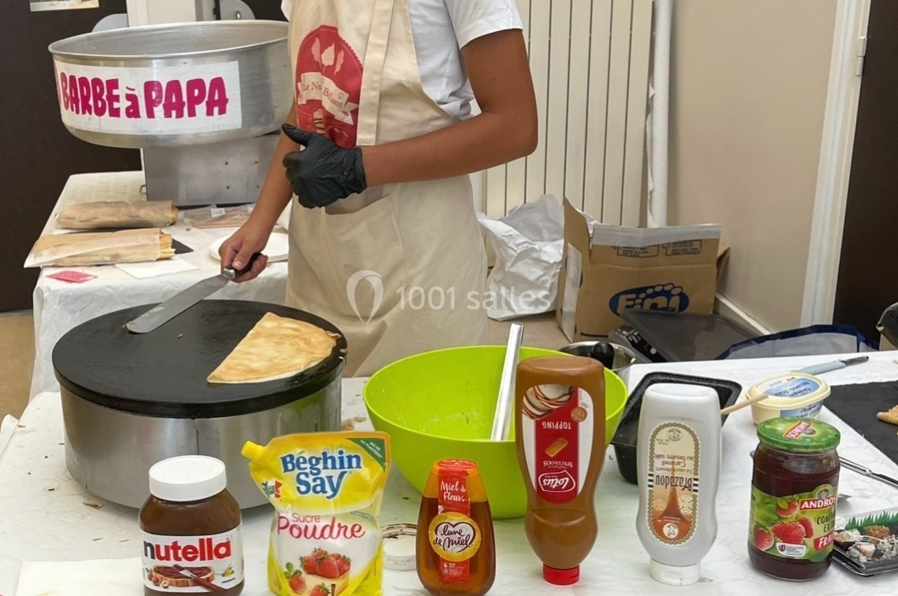 Un stand de crêpes avec une personne préparant une crêpe sur une plaque chauffante, entourée d'ingrédients variés.