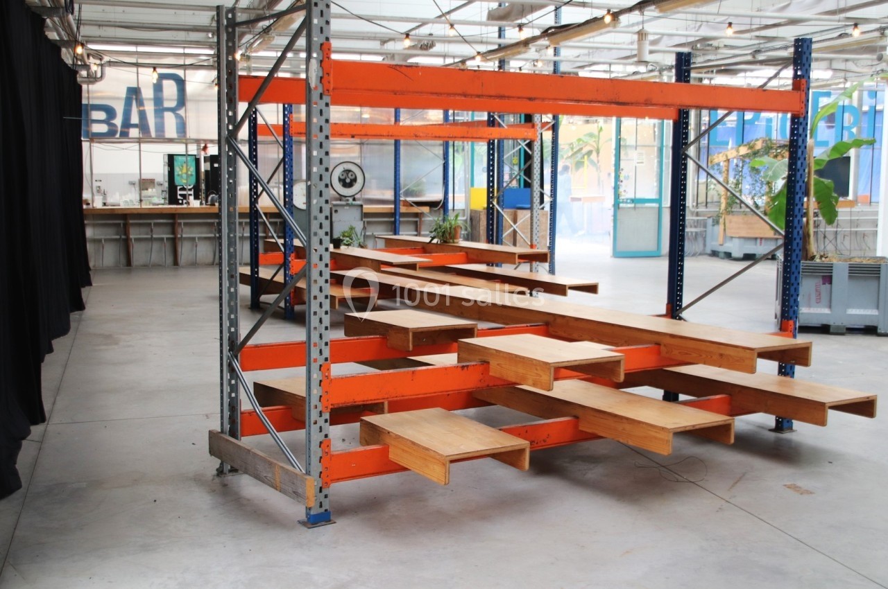 Structure métallique orange transformée en escalier avec des marches en bois, dans un espace intérieur industriel.