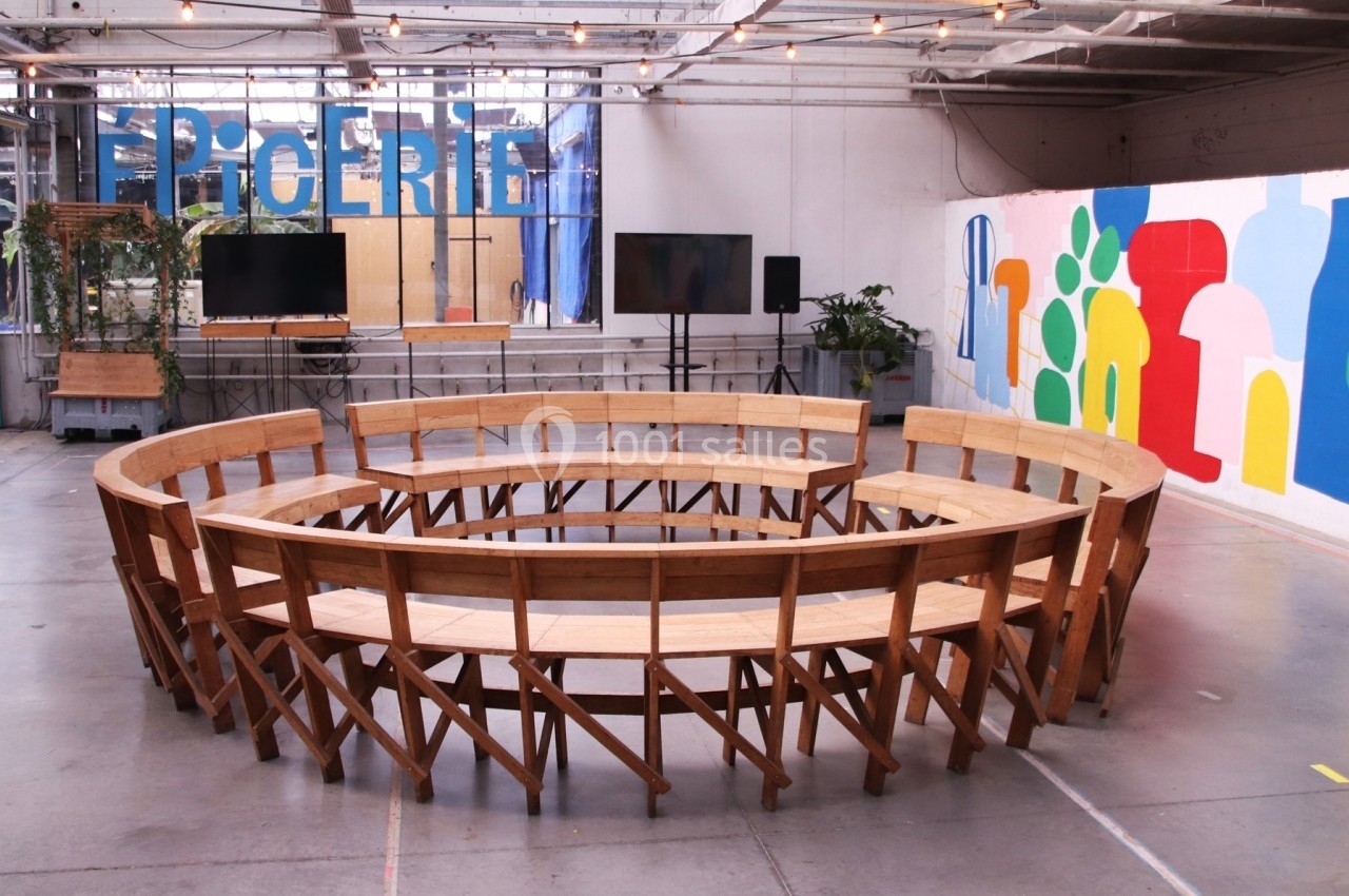 Banc circulaire en bois dans un espace intérieur lumineux avec des murs décorés de peintures colorées.