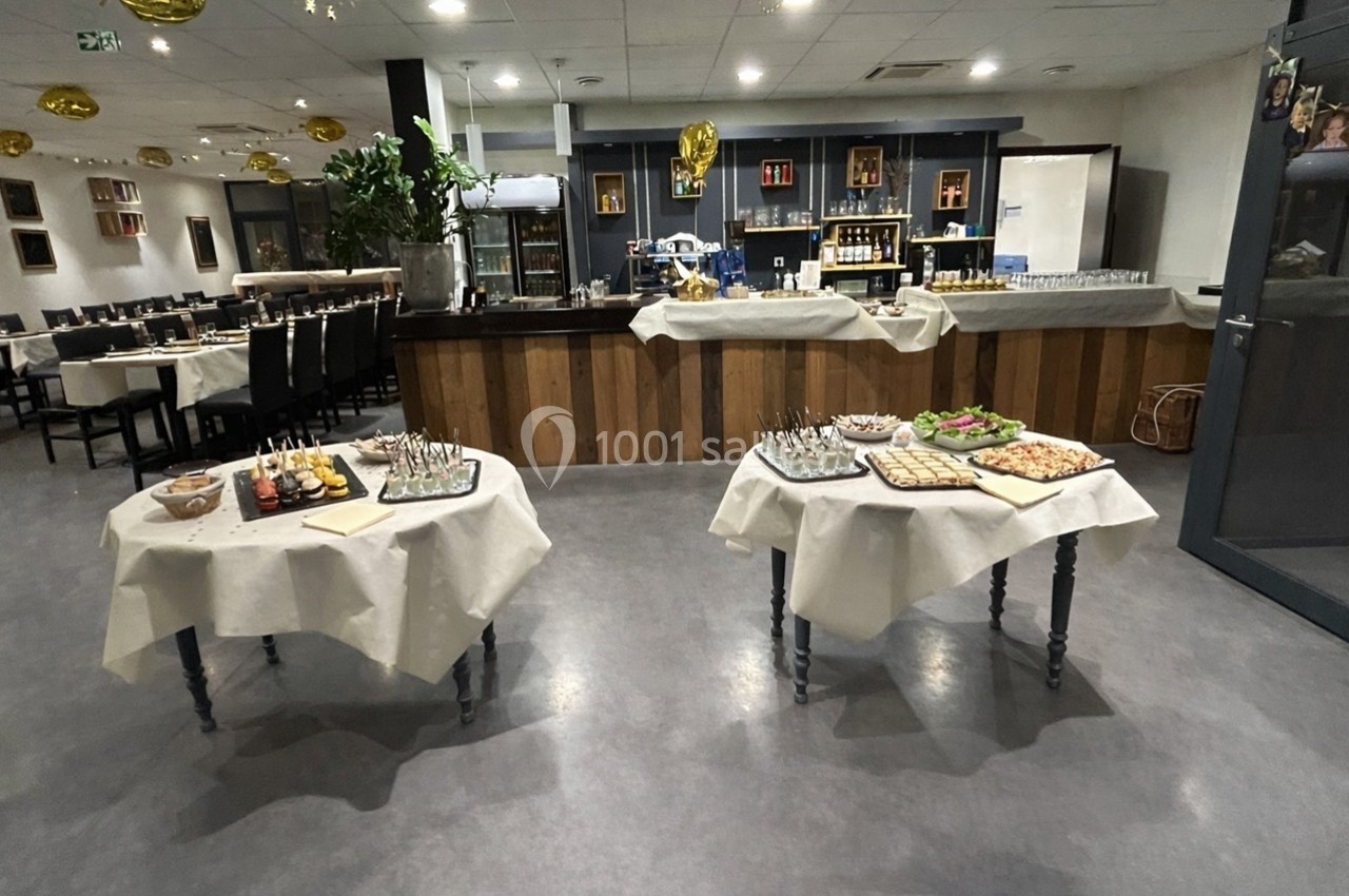 Salle de réception avec tables dressées pour un buffet, comprenant divers plats et boissons.