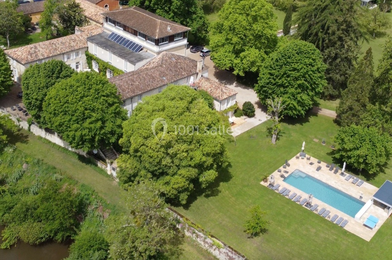 Vue aérienne d'une grande propriété avec piscine, entourée d'arbres et située près d'un cours d'eau.