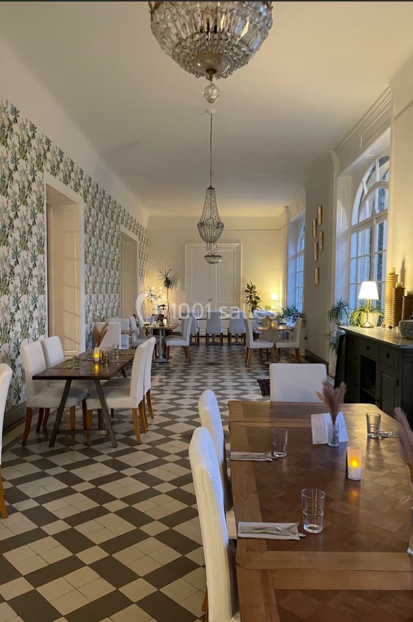 Salle de restaurant lumineuse avec tables en bois, chaises blanches, sol à carreaux et décoration élégante.