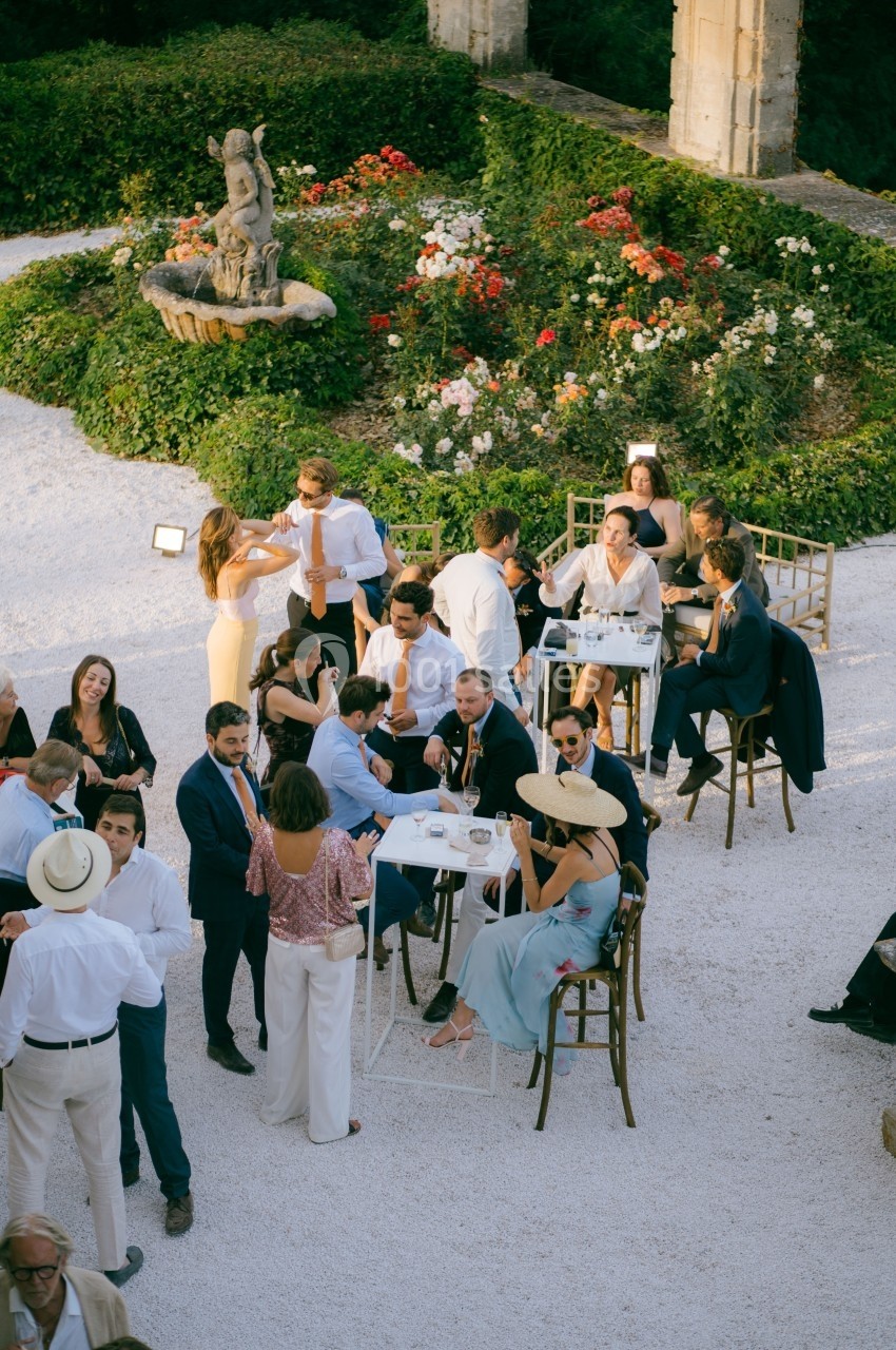 Groupe de personnes élégamment vêtues discutant et partageant un moment convivial dans un jardin fleuri.