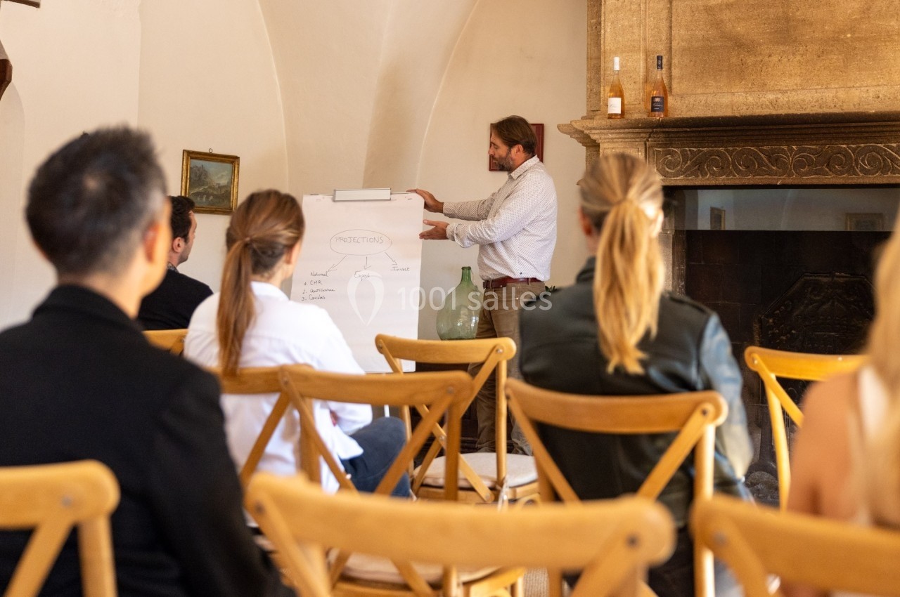 Un homme présente un schéma sur un tableau devant un petit groupe de personnes assises dans une salle.