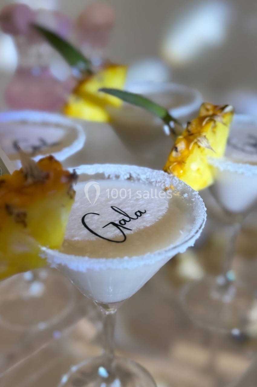 Verres à cocktail garnis de morceaux d'ananas et de sucre sur le rebord, avec une inscription sur la mousse.