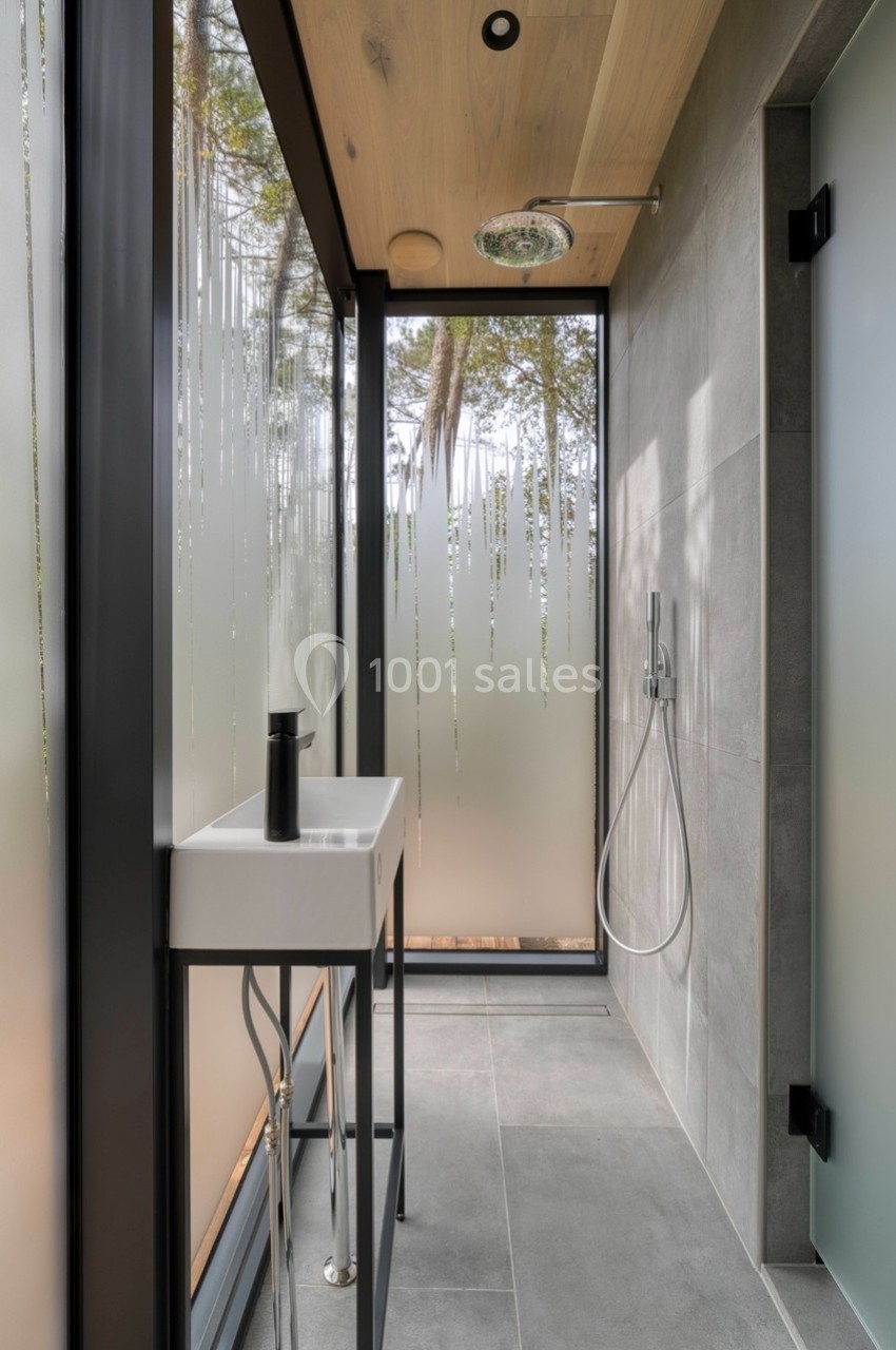 Salle de bain moderne avec douche à l'italienne, lavabo minimaliste et parois vitrées partiellement dépolies.