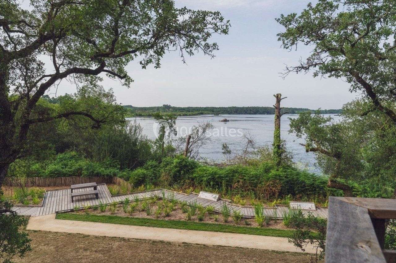 Vue sur un fleuve entouré de végétation, avec une promenade en bois et un chemin aménagé au premier plan.