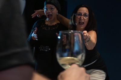 Deux personnes discutent dans un groupe lors d'un événement, l'une souriante et l'autre regardant vers l'objectif.