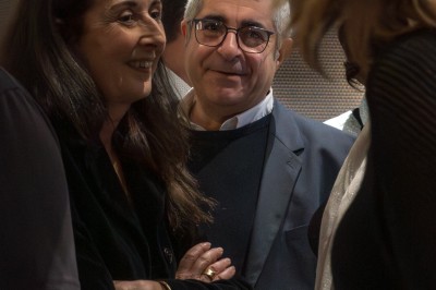 Deux personnes discutent dans un groupe lors d'un événement, l'une souriante et l'autre regardant vers l'objectif.