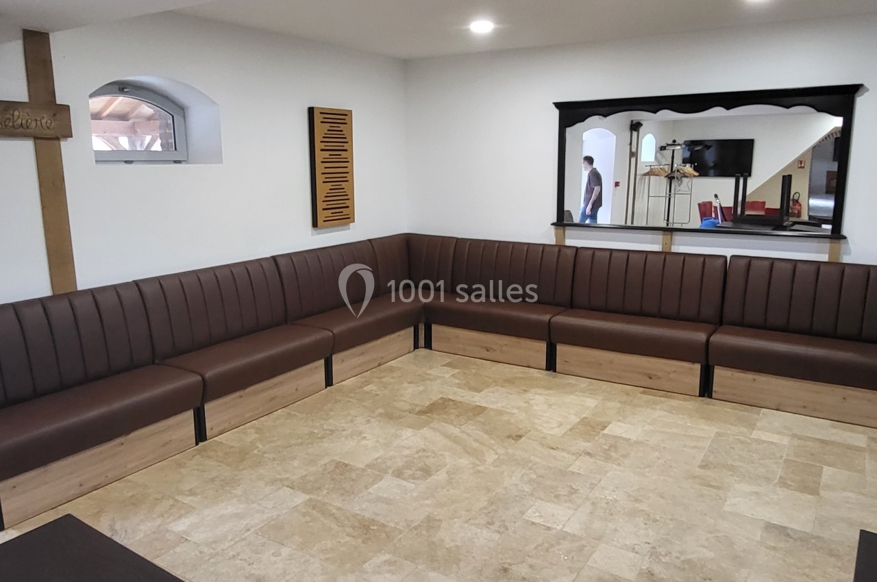 Banquette d'angle en bois et cuir brun dans une pièce lumineuse avec sol en carrelage beige et miroir mural.