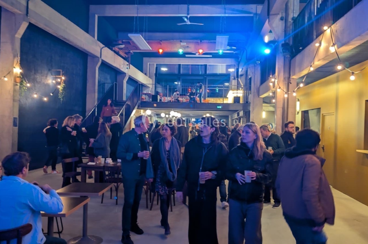 Personnes discutant dans un espace intérieur lumineux avec des guirlandes et une ambiance conviviale.