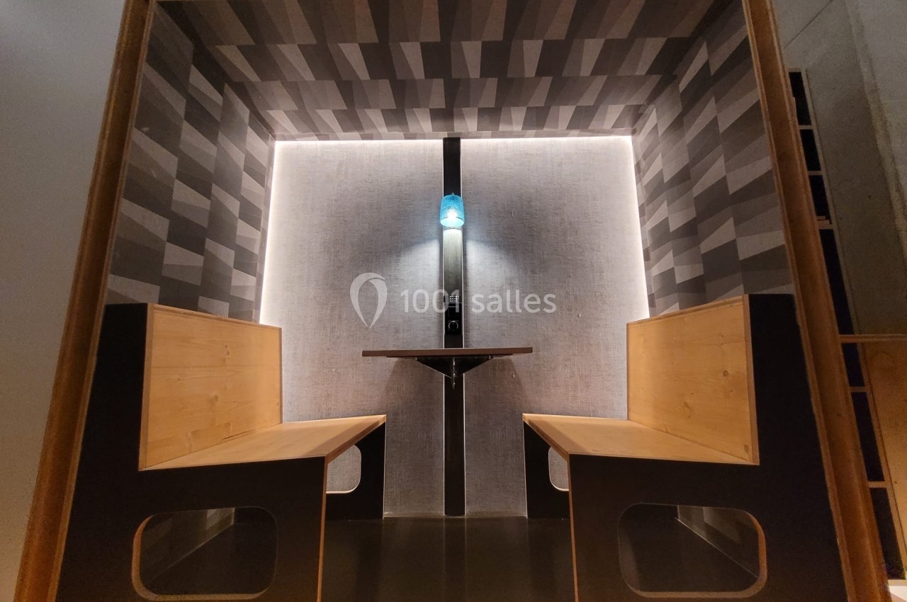 Cabine en bois avec deux bancs face à face, éclairage intégré et paroi arrière au design géométrique.