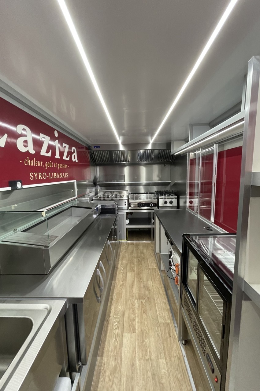 Intérieur d'une cuisine professionnelle moderne avec équipements en inox et plancher en bois clair.