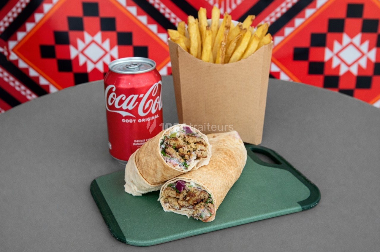 Un wrap coupé en deux avec garniture visible, accompagné de frites et d'une canette de soda sur une table.