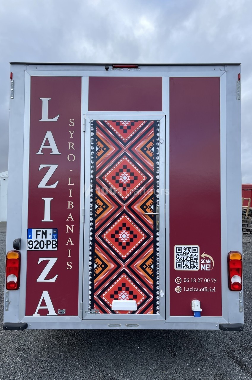 Vue arrière d'un food truck syro-libanais avec motifs colorés, numéro de téléphone et QR code visibles.