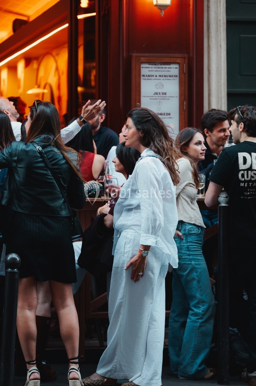Groupe de personnes discutant et partageant un moment convivial devant un bar en soirée.