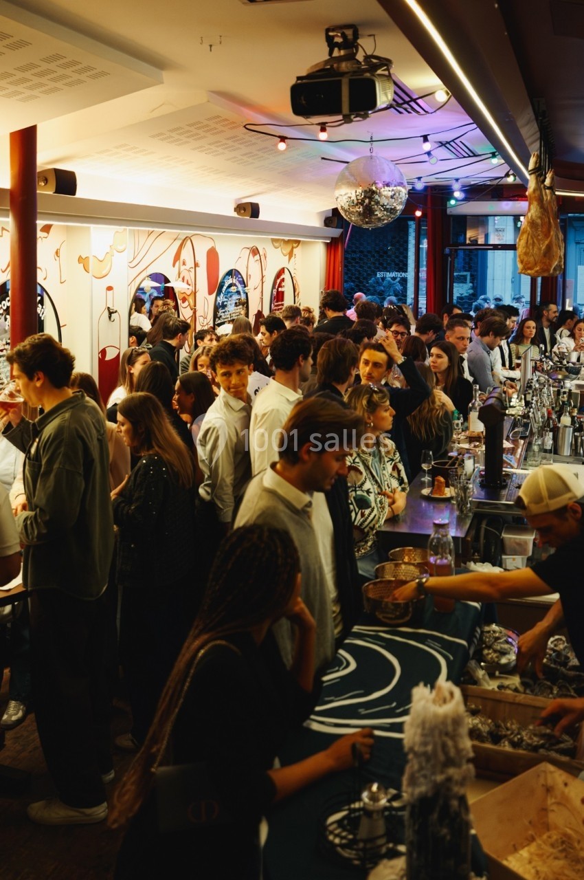 Un bar animé avec une foule de personnes discutant et se servant à un comptoir, éclairage chaleureux.