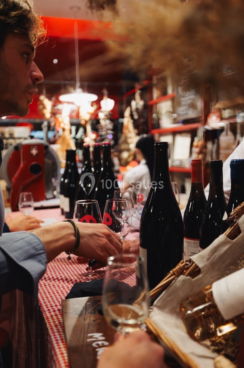 Dégustation de vin dans une ambiance chaleureuse, avec des bouteilles exposées sur une table à nappe rouge.