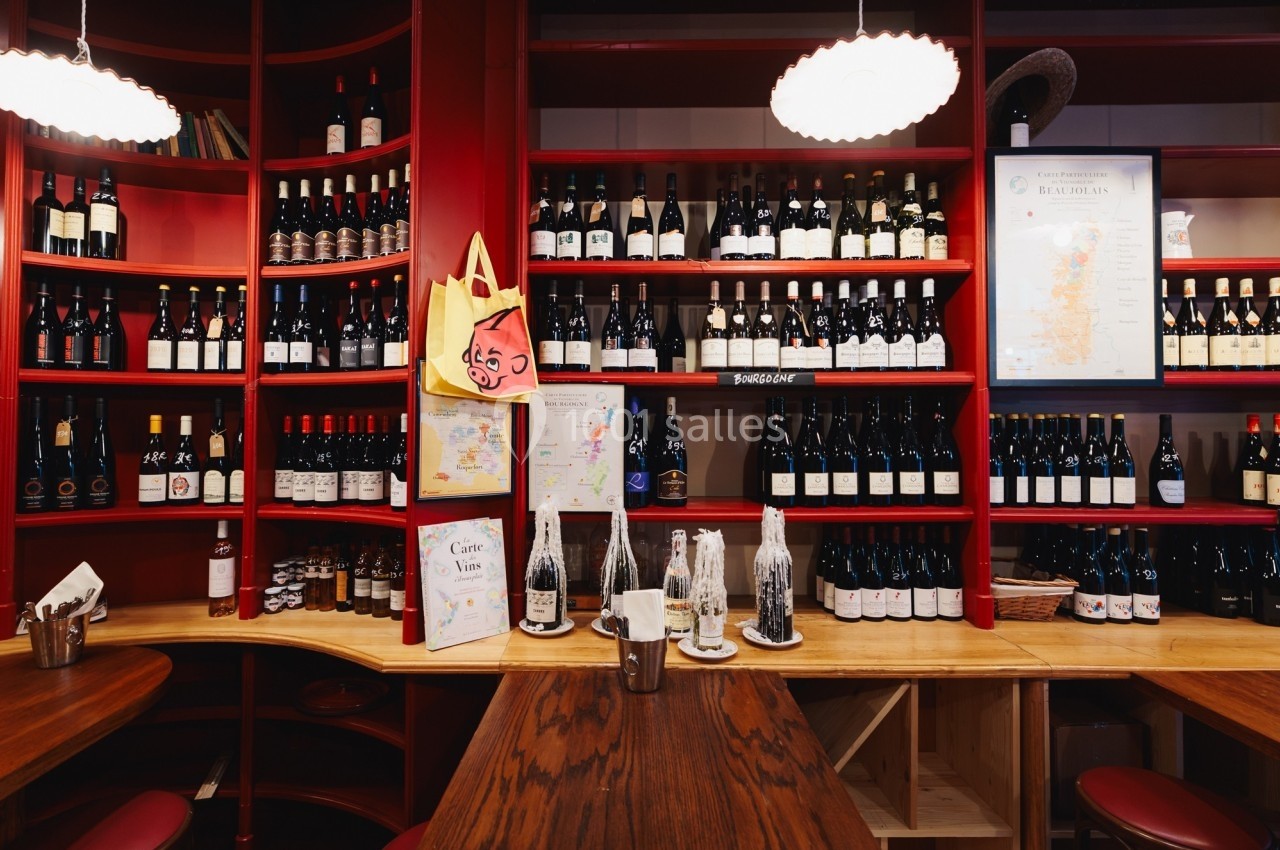 Étagères remplies de bouteilles de vin dans un intérieur de cave à vin avec des cartes et des décorations murales.