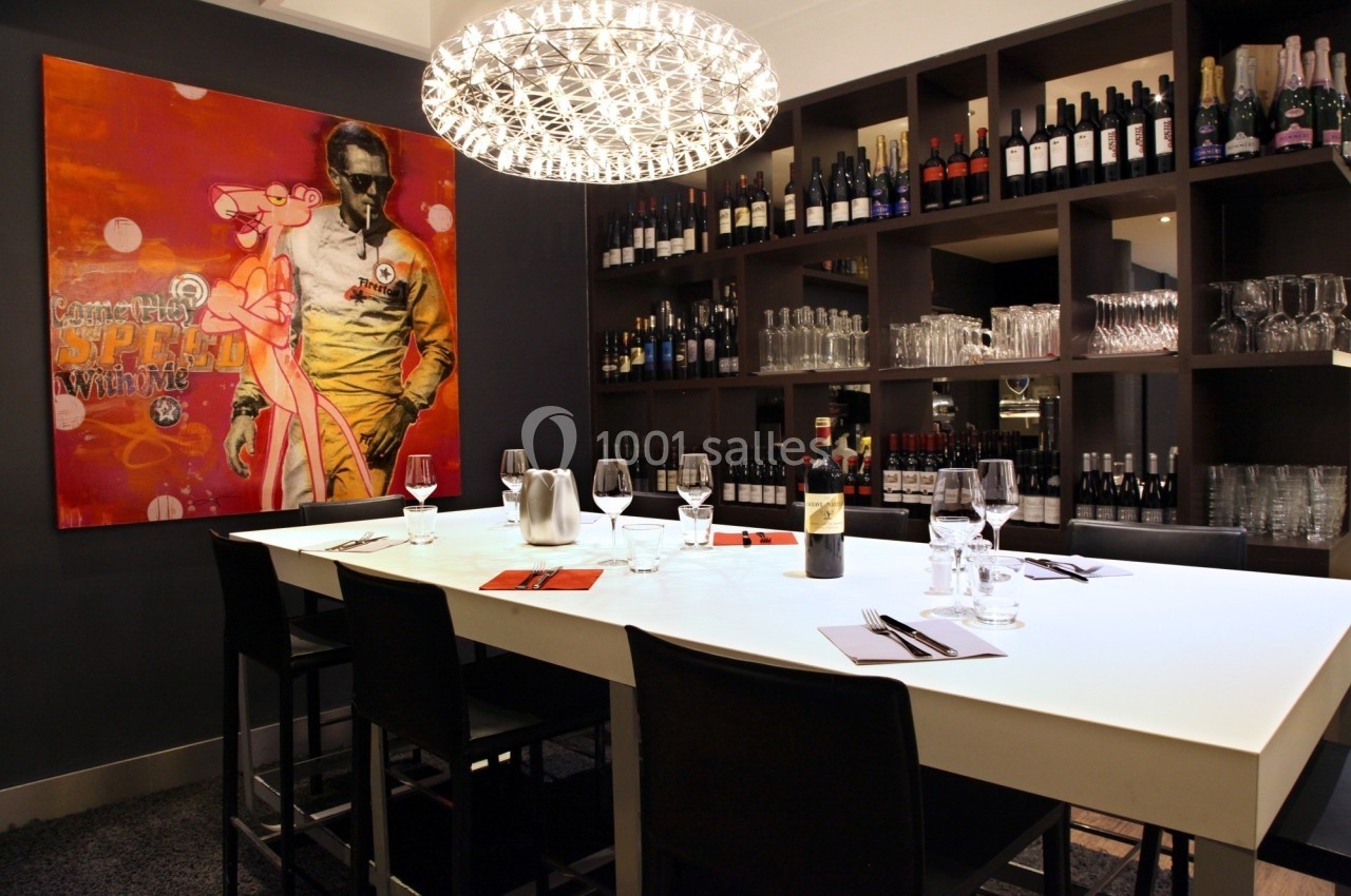 Table dressée dans un restaurant moderne, entourée d'étagères avec des bouteilles de vin et décorée d'une peinture colorée.