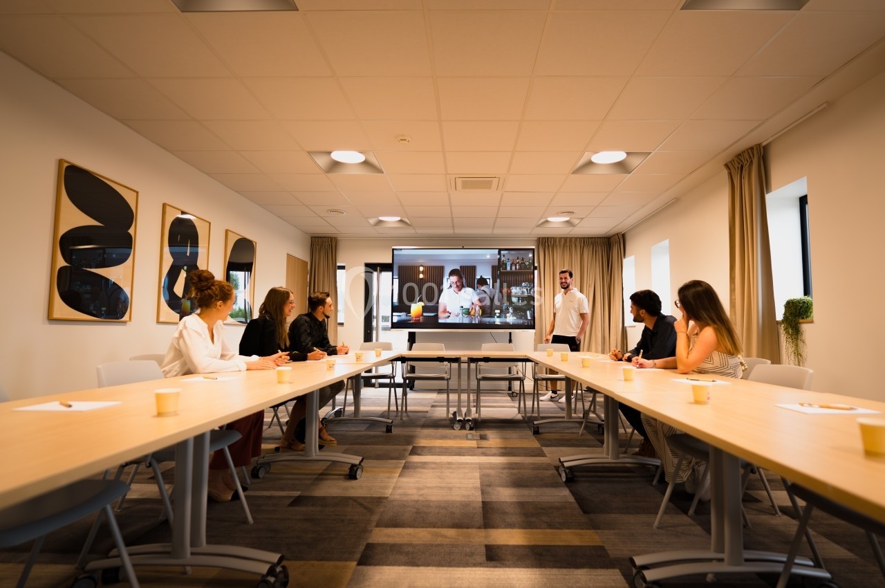 Un groupe de personnes assises dans une salle de réunion regarde une présentation projetée sur un écran.