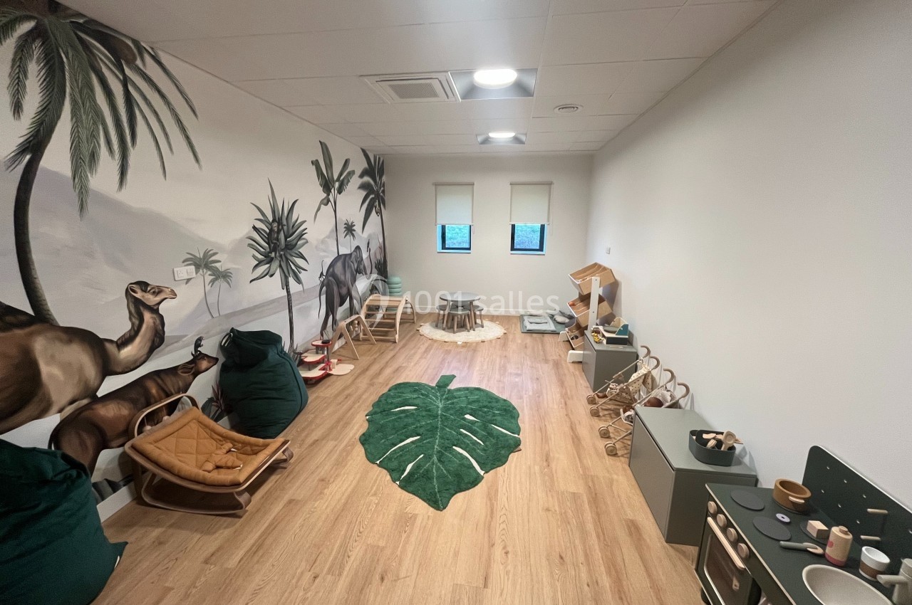 Salle de jeux pour enfants avec décor mural de nature, tapis en forme de feuille et mobilier en bois.