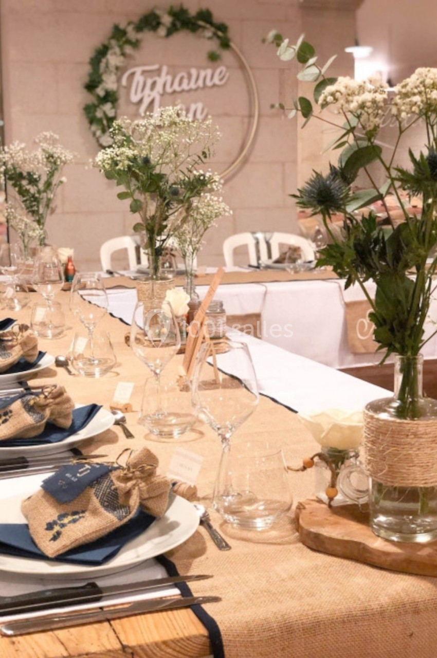 Table décorée pour un mariage avec nappes en toile de jute, fleurs sauvages et vaisselle élégante.