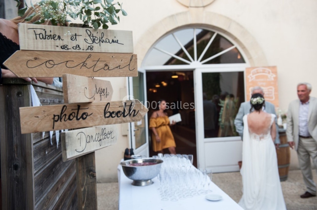 Panneaux en bois indiquant ’cocktail’ et ’photo booth’ lors d'une réception en extérieur devant une salle.
