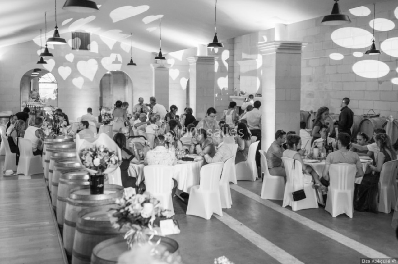 Salle de réception décorée, invités assis à des tables rondes, ambiance festive avec éclairages en forme de cœurs.