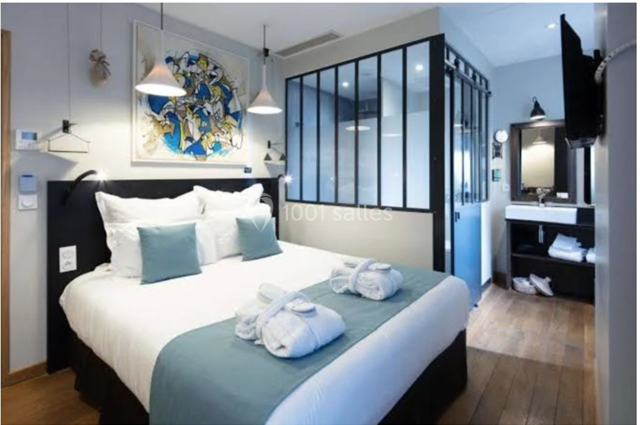 Chambre d'hôtel moderne avec lit double, décoration épurée, salle de bain attenante et lumière naturelle.