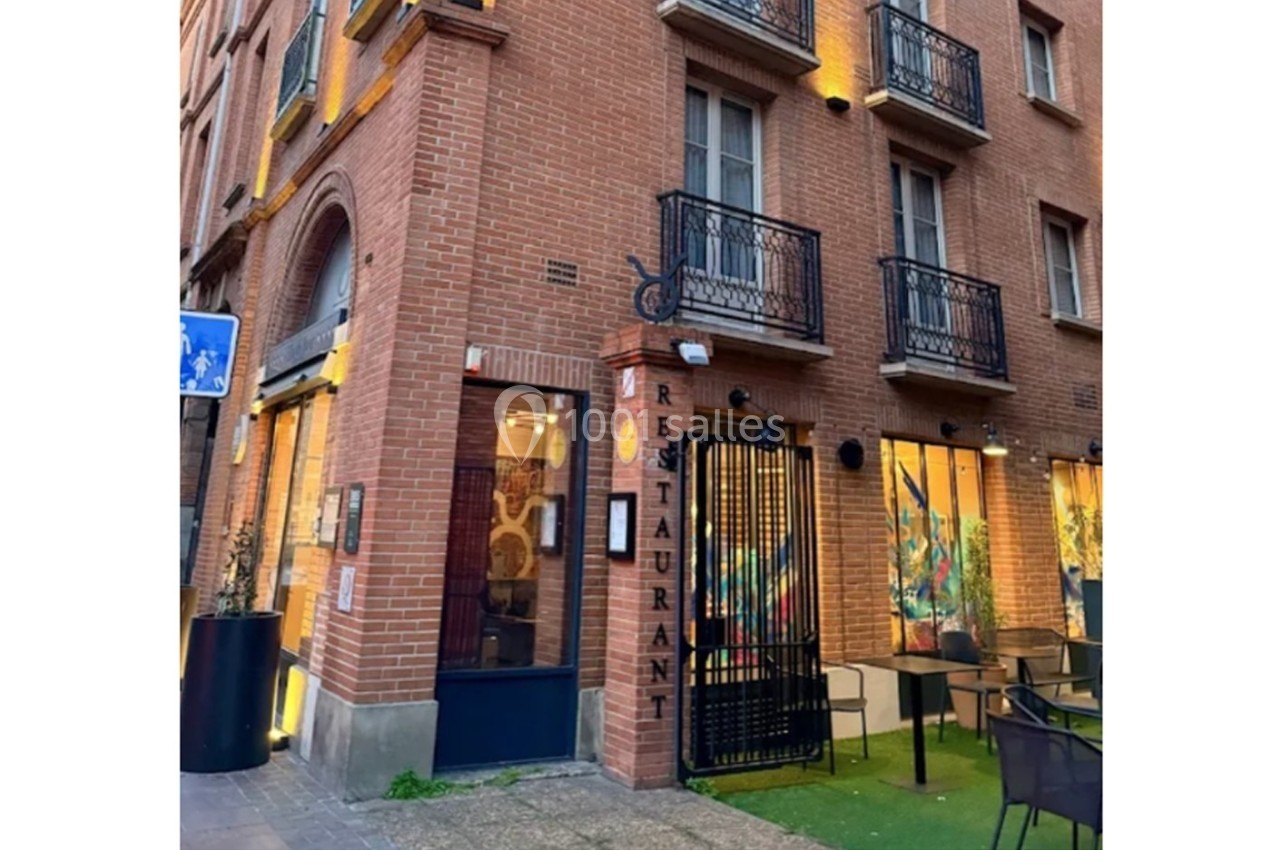 Façade en briques d'un restaurant avec terrasse extérieure et enseigne verticale indiquant ’Restaurant’.
