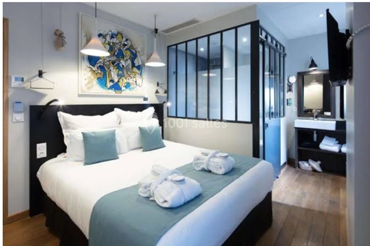 Chambre d'hôtel moderne avec lit double, verrière, salle de bain attenante et décoration épurée.