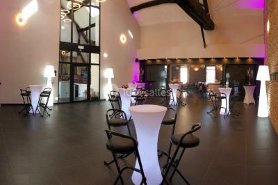 Tente blanche avec toit pointu et bordure rouge installée dans un jardin arboré, entourée de tables et chaises.