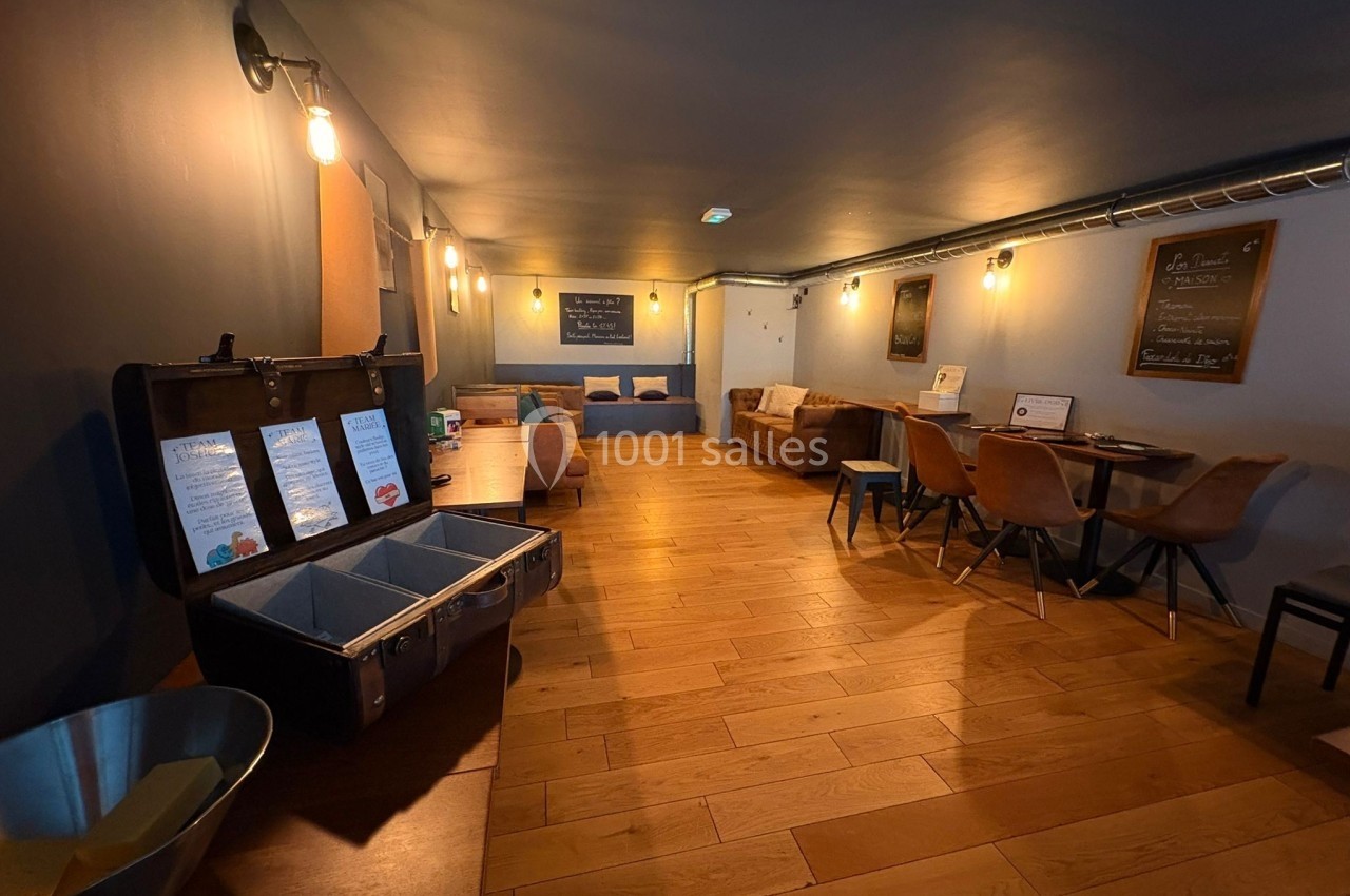 Salle chaleureuse avec parquet, mobilier en bois et éclairage tamisé, comprenant tables, chaises et décorations murales.