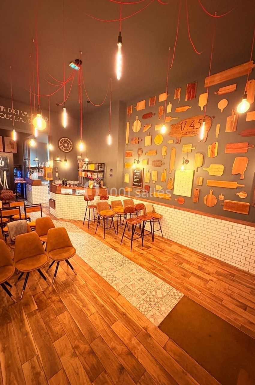 Salle de restaurant chaleureuse avec murs décorés de planches en bois, éclairage suspendu et mobilier en bois et velours.
