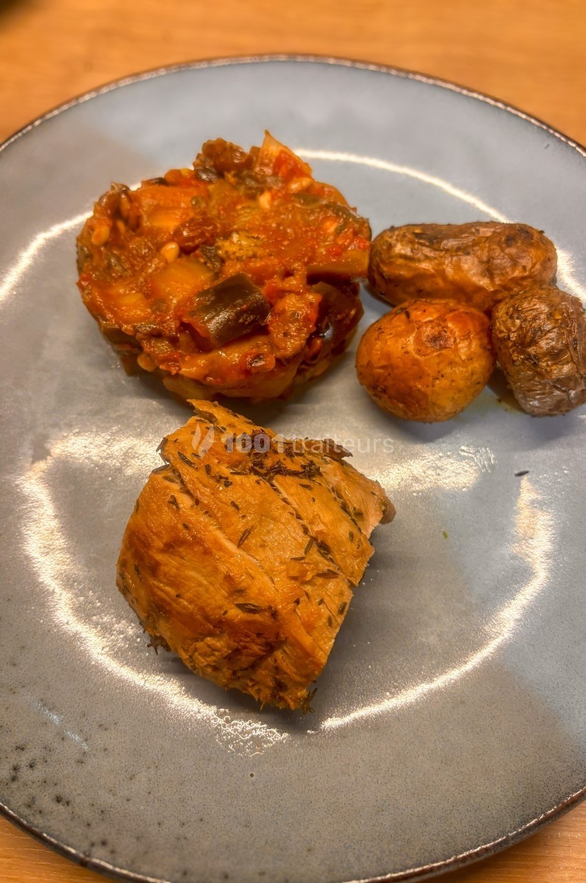 Assiette contenant un morceau de viande, des pommes de terre rôties et une portion de ratatouille.